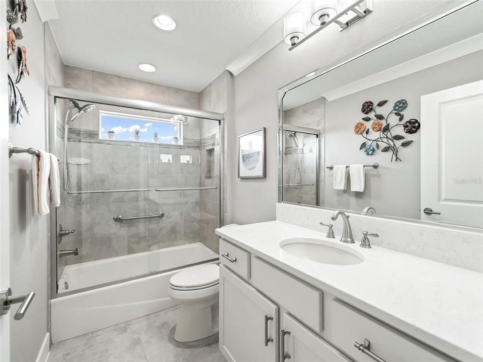 Light and Bright Guest Bath, Comfort Height Vanity with Quartz Countertops. Tiled Tub/Shower with Window and Glass Doors.