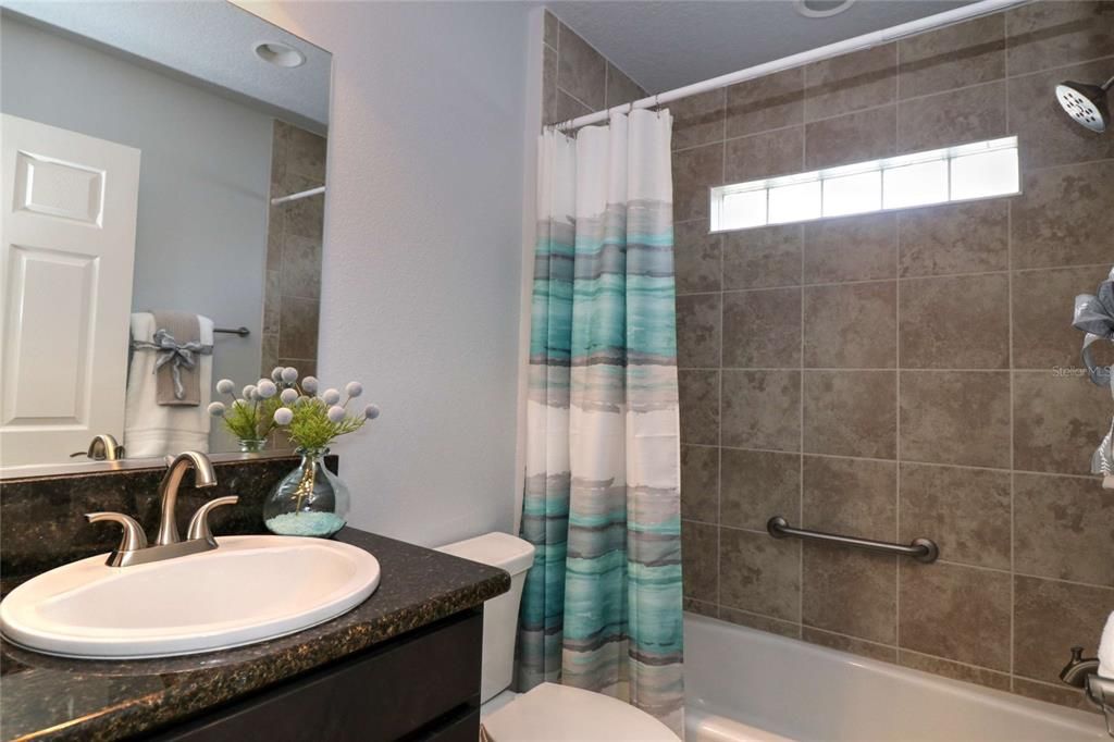 Guest bathroom has a tub and shower and granite counters