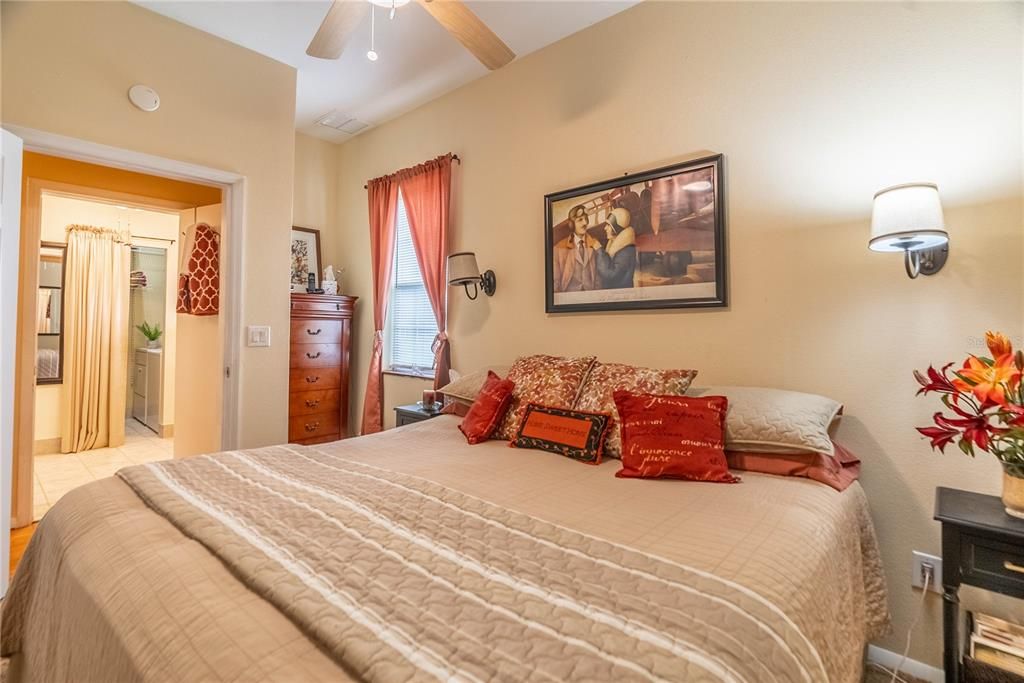 2 sconce lights adorn the wall in the master bedroom, A nook by the window provides space for drawers.