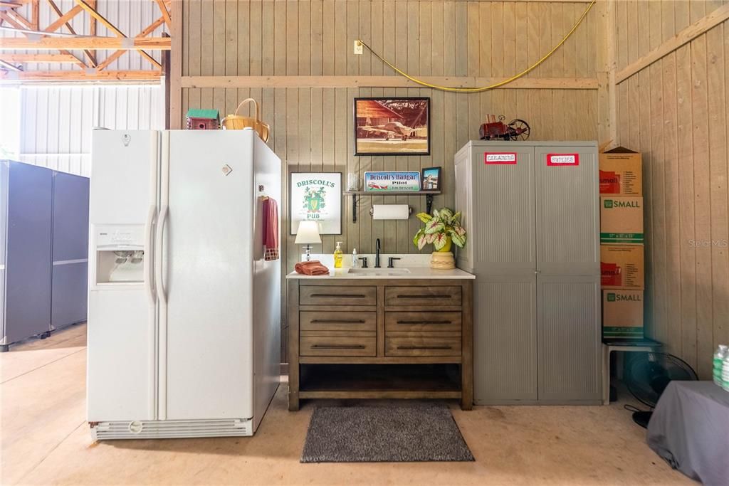 In the hangar is a sink and a second refrigerator. In front of this area to the right is a clean out if you wanted to park your RV inside the hangar. There is also the electric plug in for RV and access to water.