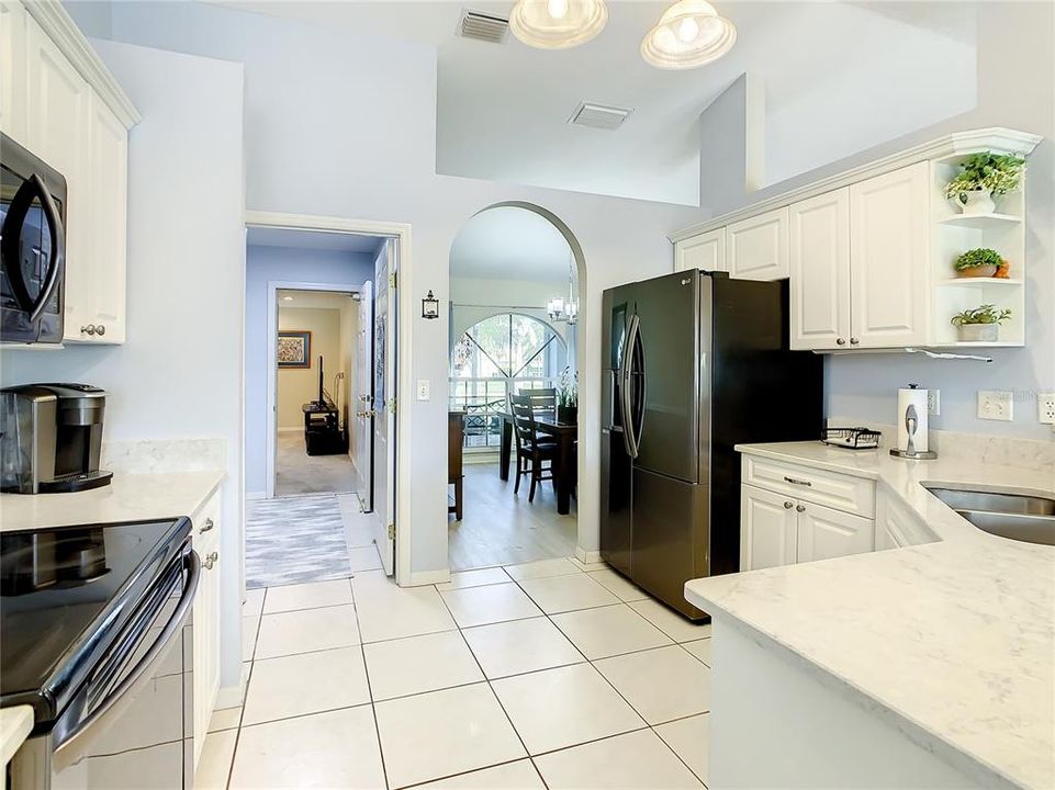 View of the kitchen with the archway on the right leading to the formal dining room and the door on the left opens to the utility room and then the family room.