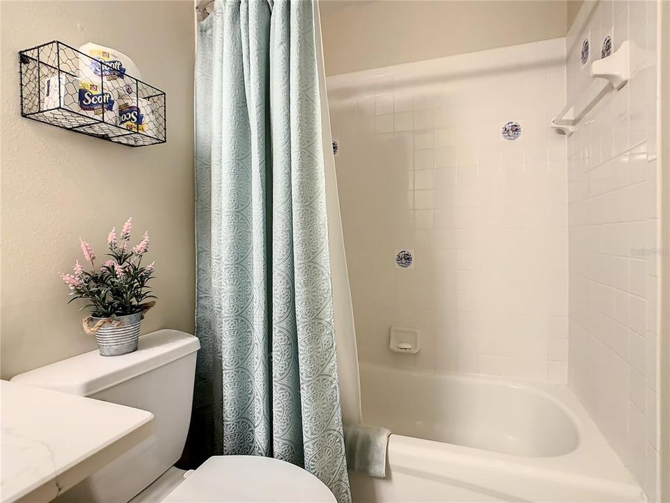Guest bathroom has tub/shower combination with neutral tile.