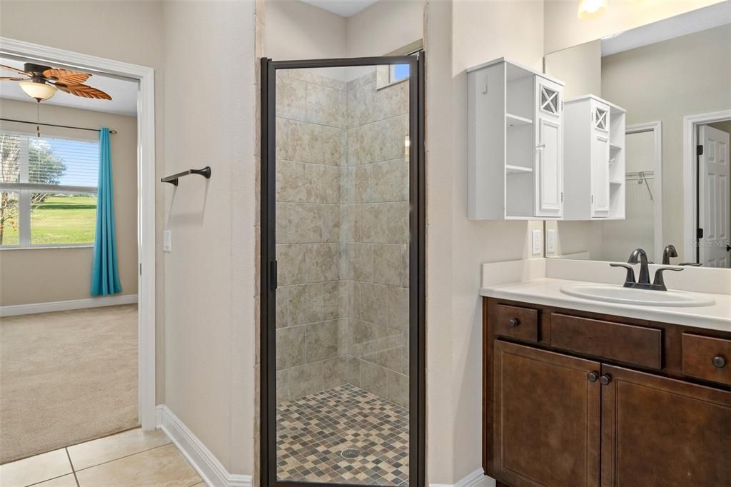 The shower is adjacent to the first vanity and is generous in size. From here you can see beyond into primary bedroom and the awesome view.