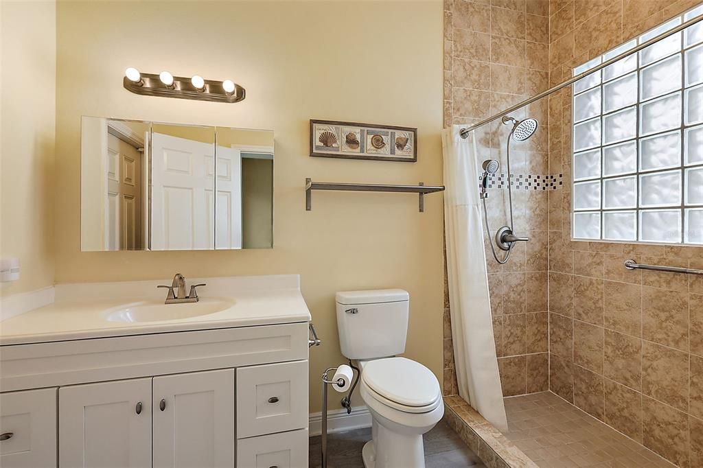 Bathroom 3 w/quartz counter, tiled walk in shower & access to lanai/pool