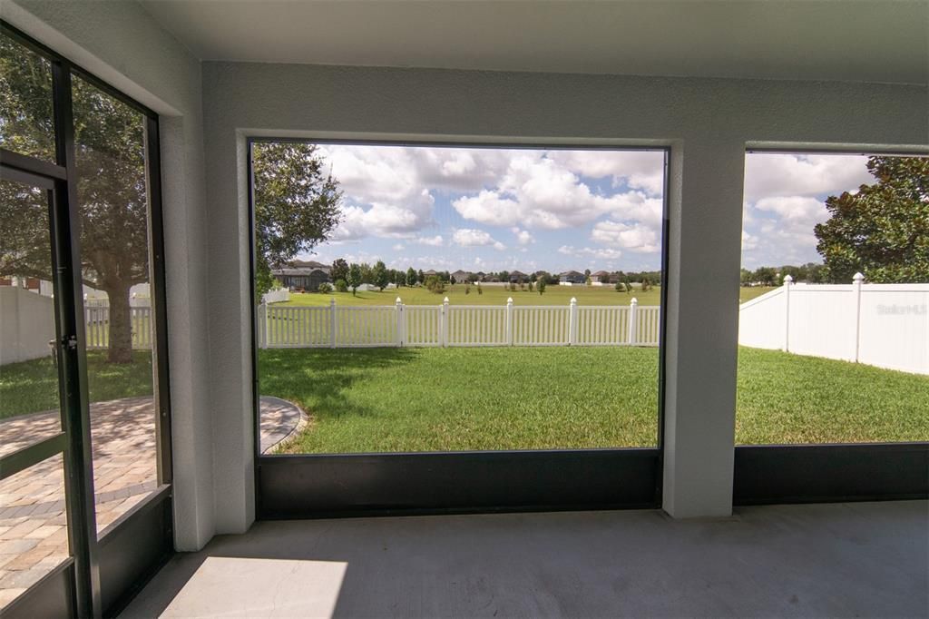 Screened Lanai overlooking fenced backyard and dry retention field beyond