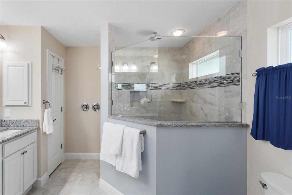 PRIMARY/MASTER BATHROOM features a DUAL SINKS, GRANITE COUNTERS, COMFORT HEIGHT TOILET, and ROMAN SHOWER w/ RAINDROP SHOWER HEAD & HAND SHOWER HEAD