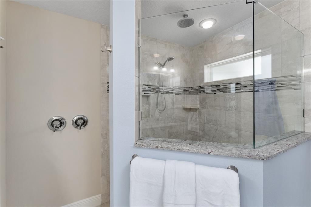 PRIMARY/MASTER BATHROOM features glass & tile ROMAN SHOWER w/ RAINDROP head & HAND HELD head. Note: Double lever water temperature control outside of TILE SURROUND at entrance.