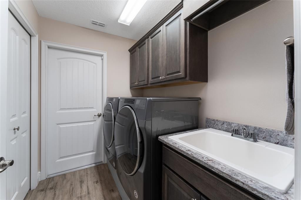INDOOR LAUNDRY ROOM features a WASHER/DRYER, laundry sink, overhead cabinets, closet & access door to 2 CAR GARAGE.