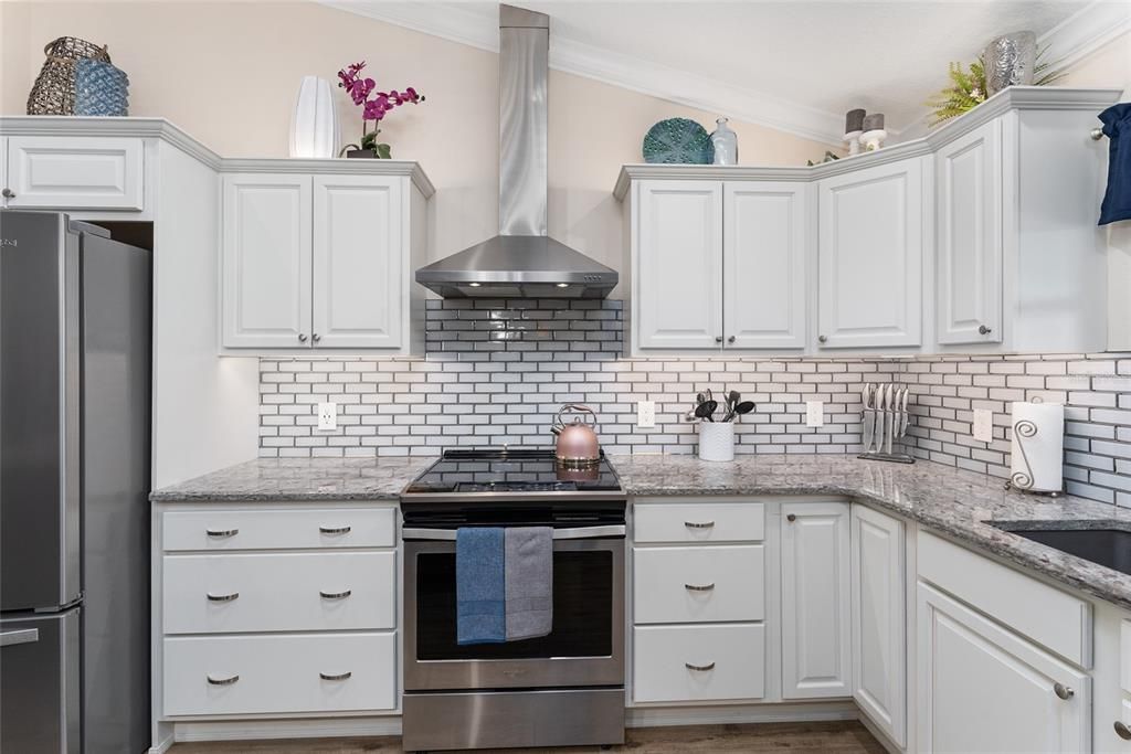 Close up view of KITCHEN w/ stunning GRANITE COUNTERS, TILE BACKSPLASH, and OVER/UNDER CABINET LIGHTING