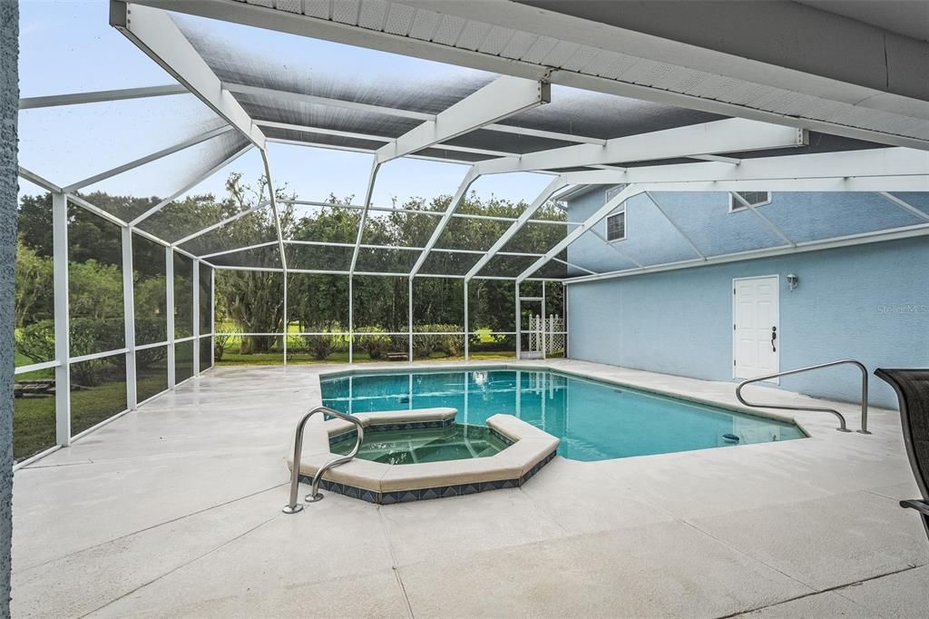 A stunning pool featuring a luxurious jacuzzi and ample space to unwind and savor the outdoors amidst the beauty of nature.