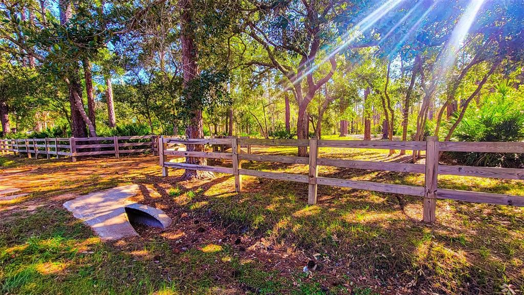 Partially fenced across the front with a split-rail wooden fence and has a DOT approved culvert