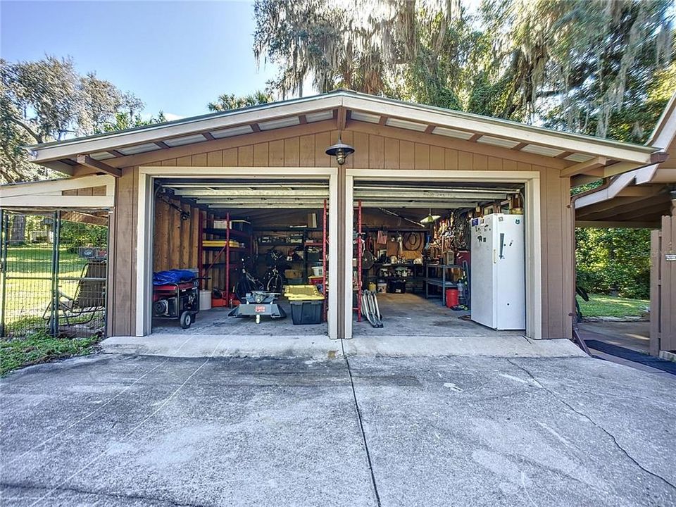 Spacious 2 car garage with workshop bench and large metal storage shelves included.