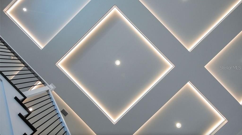 The coffered ceiling creates an architectural interest in the great room complete with custom lighting.