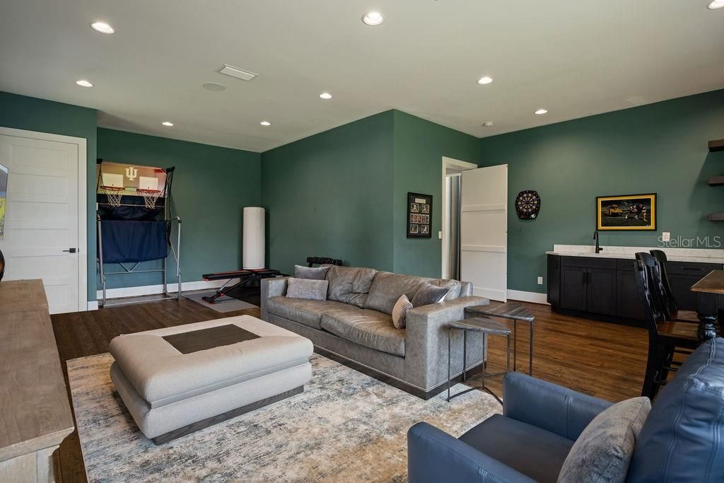 First floor media room with wet bar complete with built in storage, can lighting and engineered wood flooring.