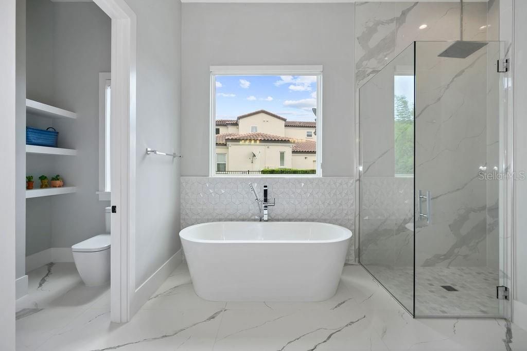 First floor master bathroom with generous soaking tub, walk in shower with floor to ceiling oversized tile and rain water shower. Separate water closet with built in shelving.