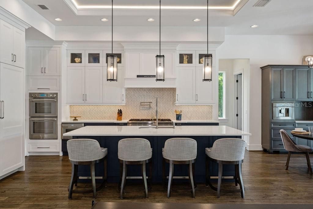 Custom cabinetry showcases ample storage, accented decorative glass front cabinets as they rise floor to ceiling and are topped off with crown molding and a tray ceiling with lighting.