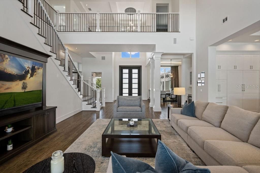 The reverse view looking back at the entry. This room is complimented with a two story coffered ceiling, wrought iron spindled staircase and neutral paint flood this great space with natural light.