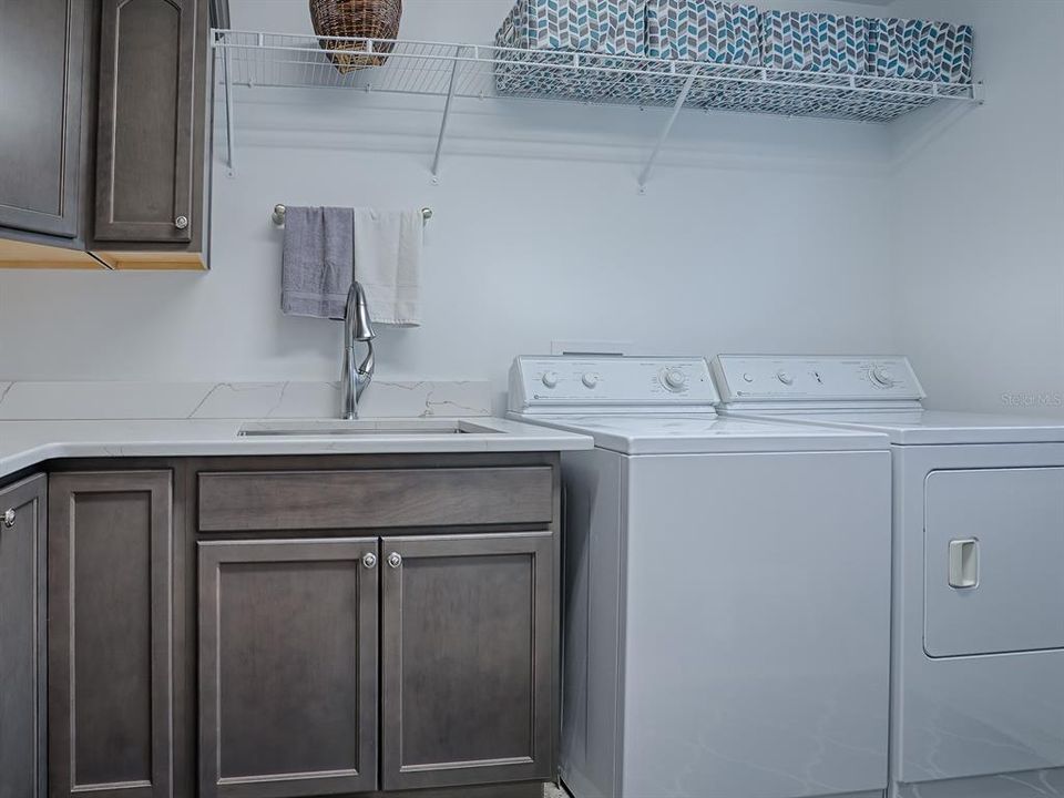LAUNDRY ROOM WITH QUARTZ COUNTERTOPS, LARGE SOAKING TUB, MORE CABINETS FOR STORAGE, WASHER AND DRYER (THEY DO CONVEY WITH THE HOME) AND EXTRA SHELVING.