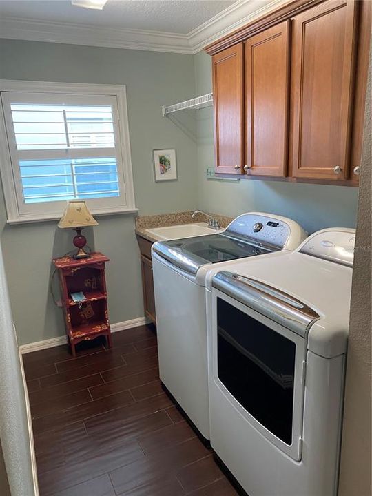 Great laundry room with utility sink, cabinets, and Whirlpool Colobria washer and dryer