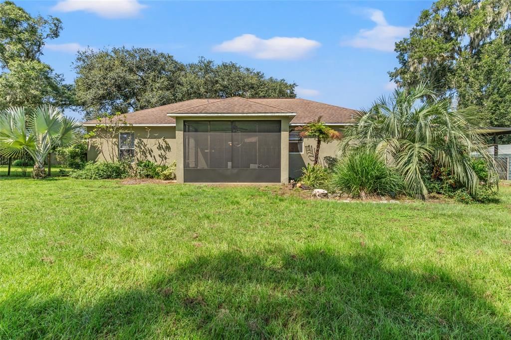 Back of home w/ screened lanai, pond and beautiful yard