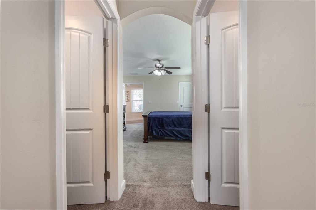 Hallway from primary bedroom to bathroom with a walk in closet on each side.