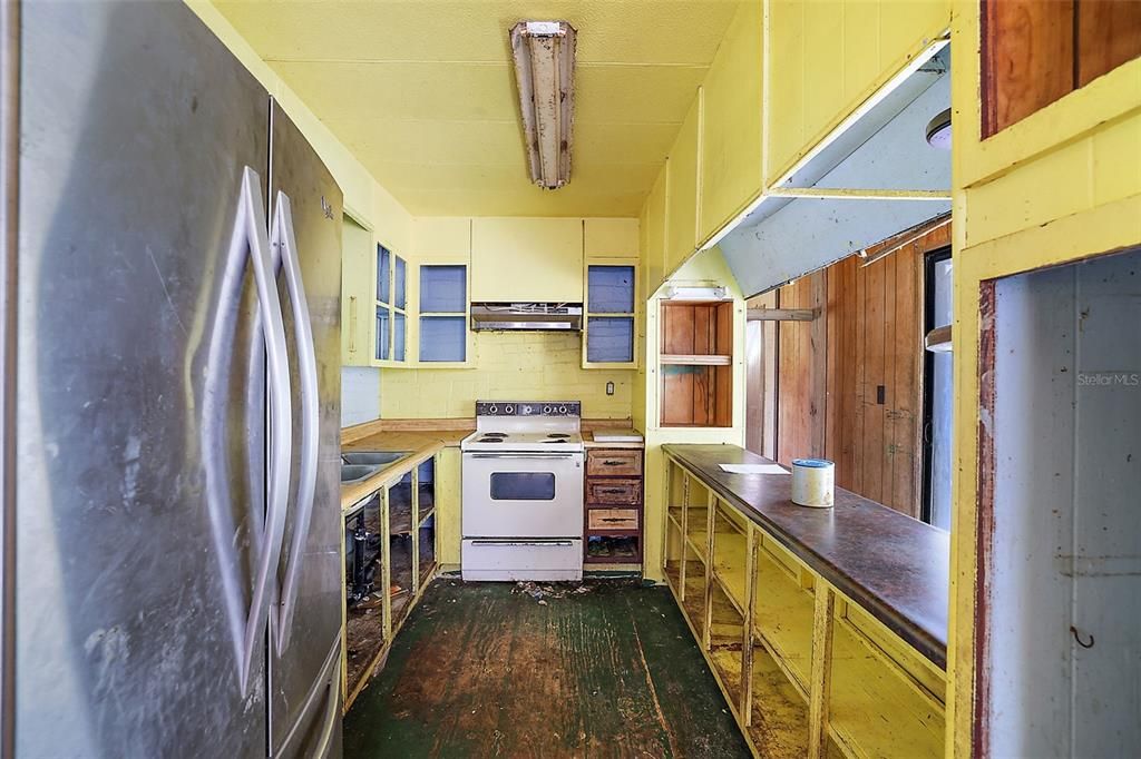 Kitchen - 08X10 - no doors on cabinets, flooring has holes, mold is evident in ceiling.