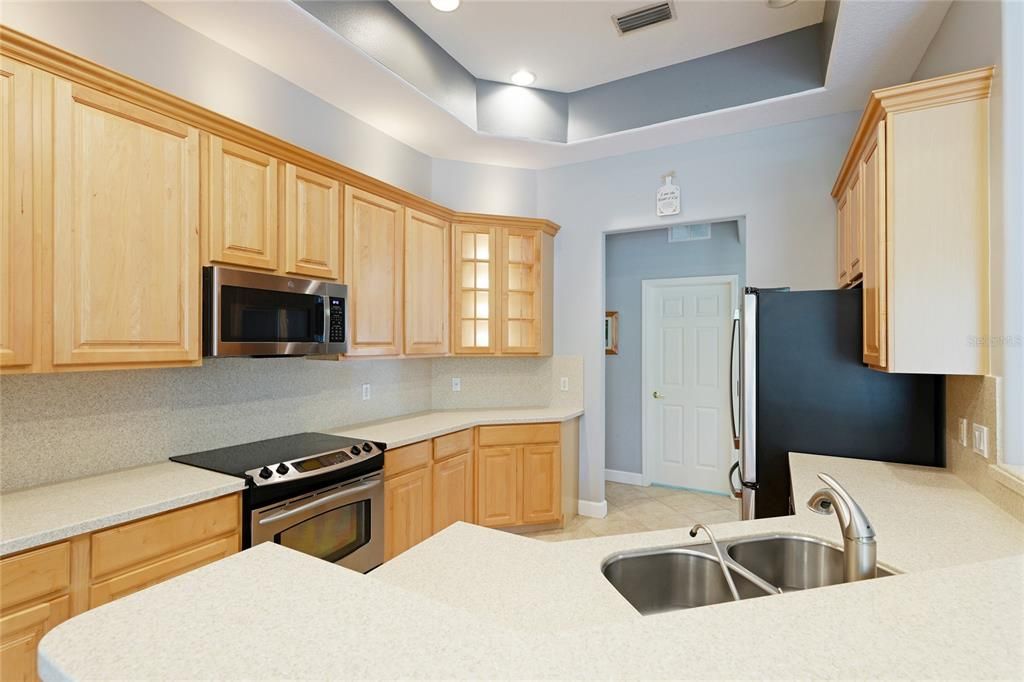 The kitchen has a coffered ceiling, stainless steel appliances, solid surface countertops, and a bar area perfect for entertaining family, friend and guest.