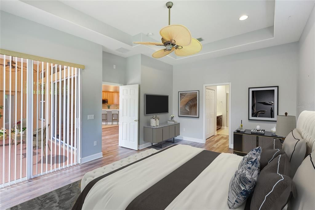 The primary suite has sliders leading to the oversize lanai, a large window overlooking the private backyard, and a transom window over the bed for even more soft sunshine. virtually staged photo