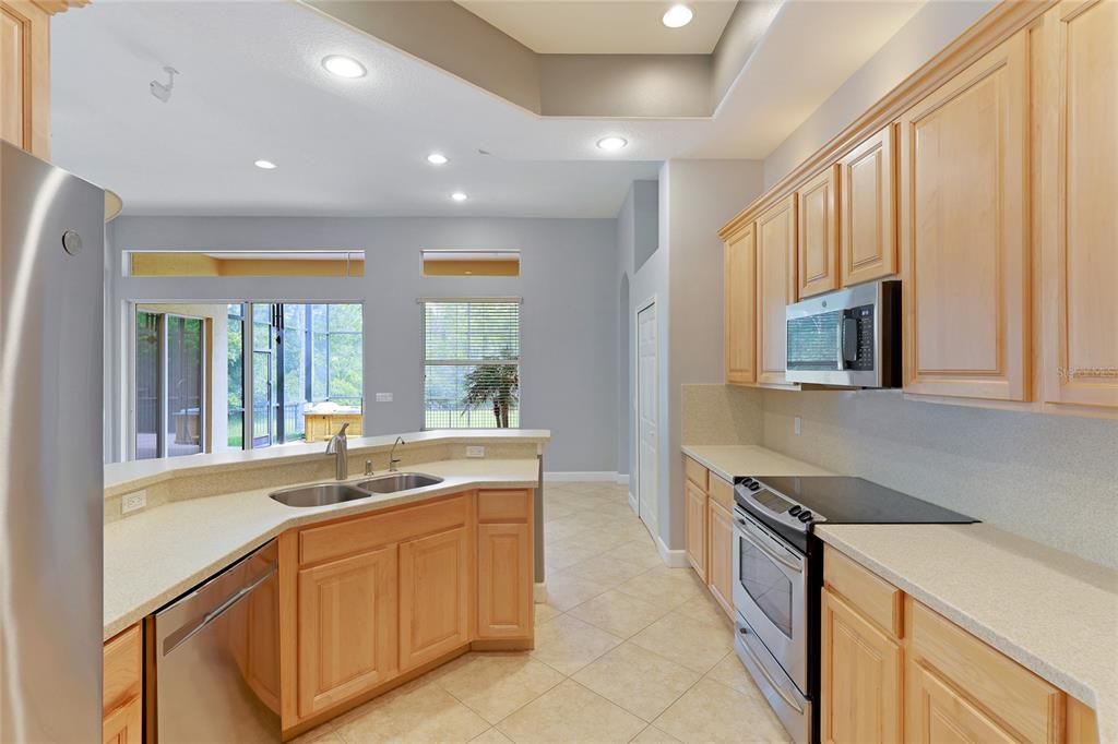 The kitchen has a coffered ceiling, stainless steel appliances, solid surface countertops, and a bar area perfect for entertaining family, friend and guest.