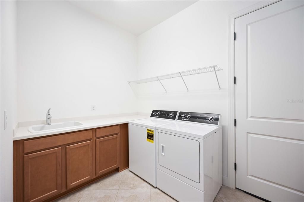 The laundry room has a utility sink and on the opposite wall not pictured are more cabinets/countetops.