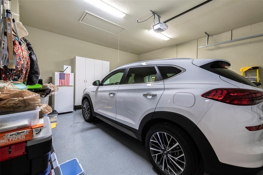 Garage with epoxy floors, attic access and cabinets