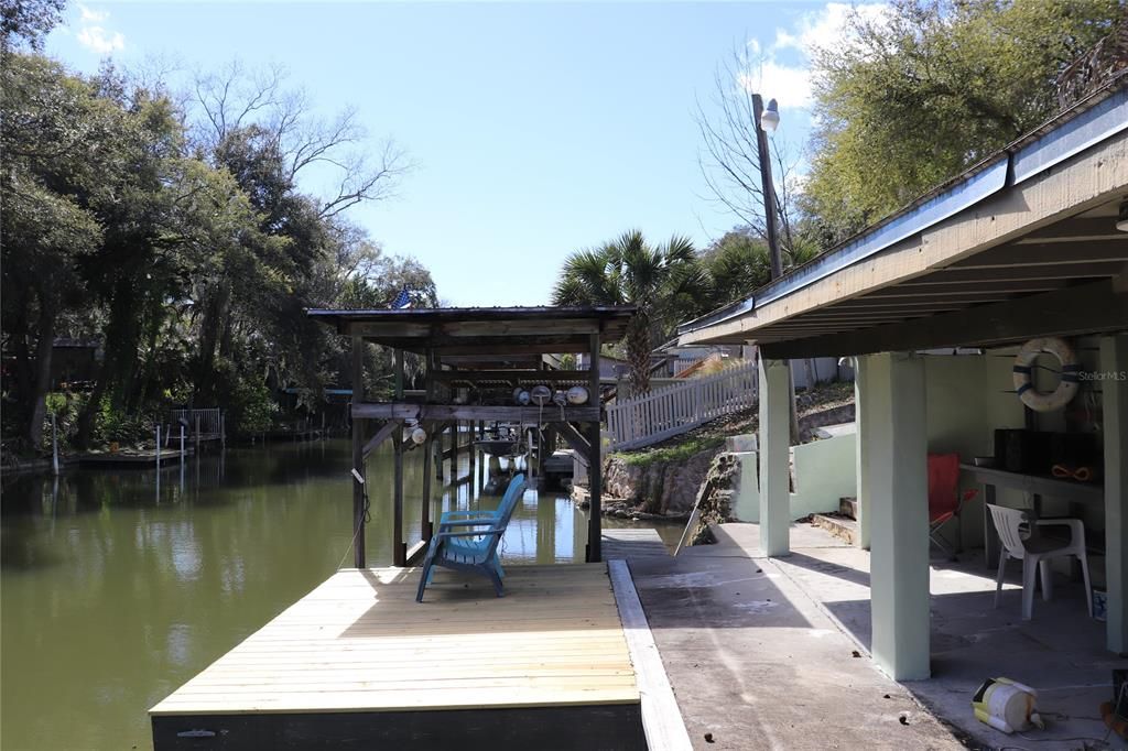 Looking from the West side of the canal front property at the boat dock, boat house, and the roofed outdoor recreation area.