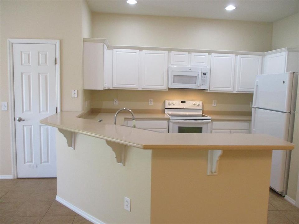 KITCHEN WITH SOLID SURFACE COUNTERS, LARGE BREAKFAST BAR.
