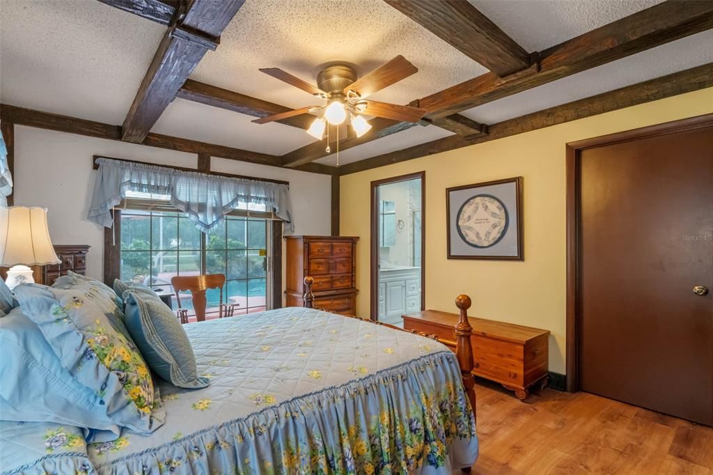 Master bedroom with wood beam ceilings and Oak Hardwood Floors. Slider leads out to enclosed pool area.
