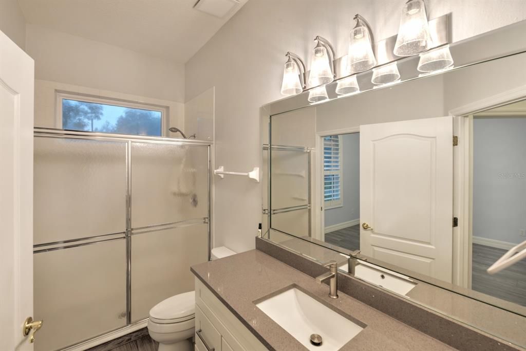 Guest bath off guest bedroom with pocket doors makes it a private suite. Quartz counters with walk-in shower.