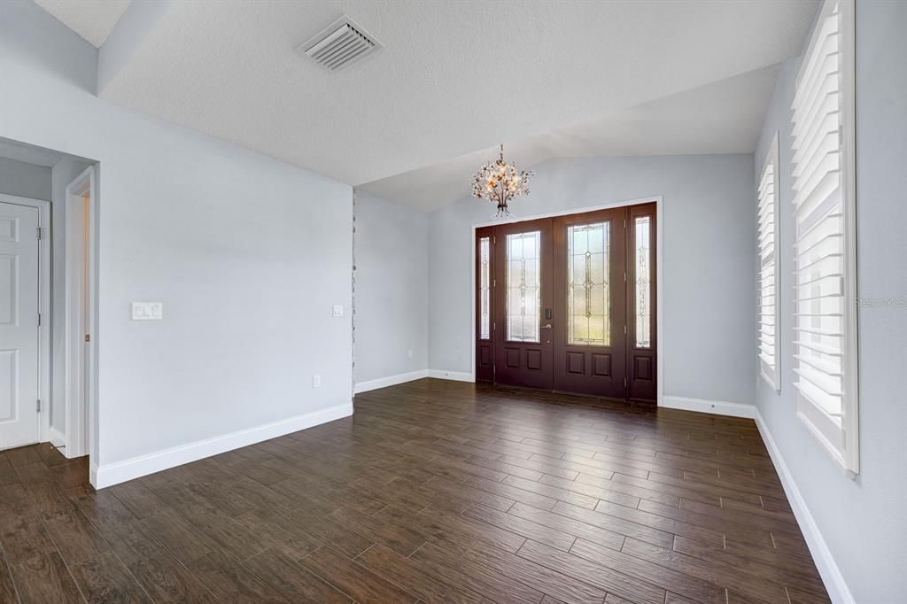 Large foyer or receiving area off the front door. Shutters on the windows.  Bathroom to the left side of foyer.