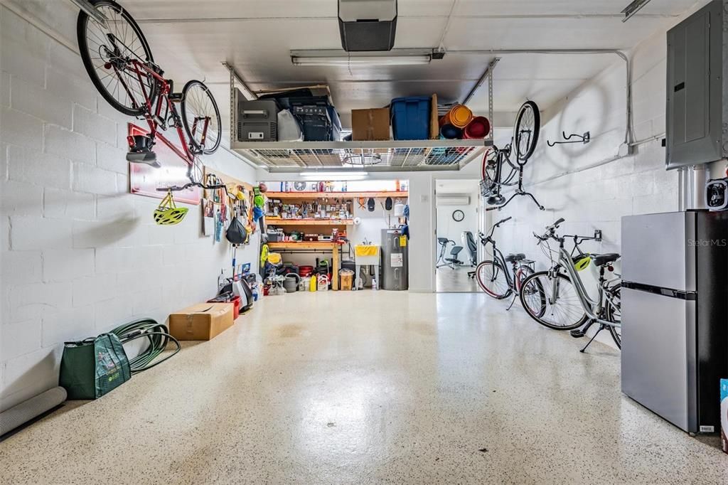 Oversized garage with hanging storage rack, custom built in work bench, utility sink, peg boards for additional storage