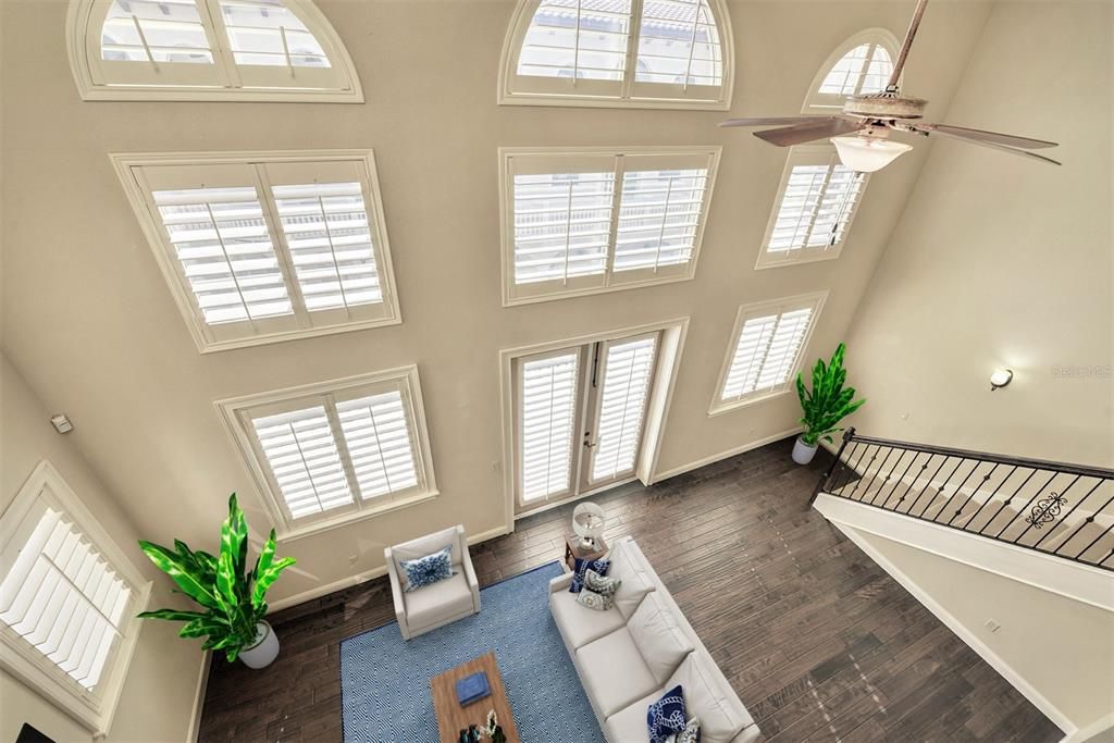 Two story living room with floor to ceiling windows and plantation shutters.