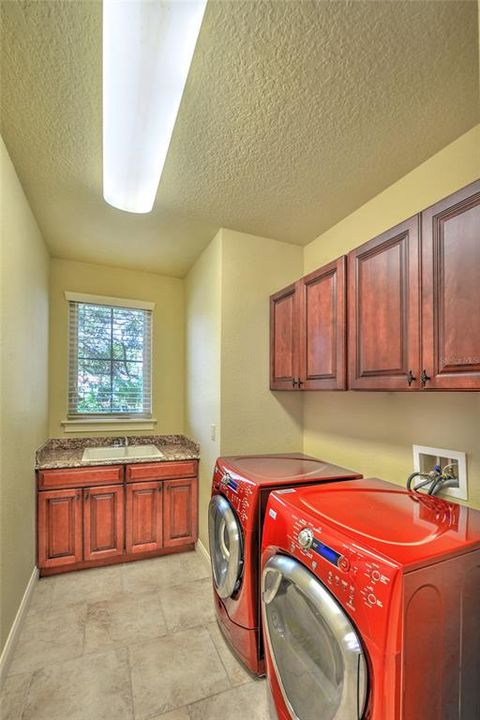 Inside laundry with built-in splash tub, granite counter, built-in cabinetry, and washer/dryer combo.