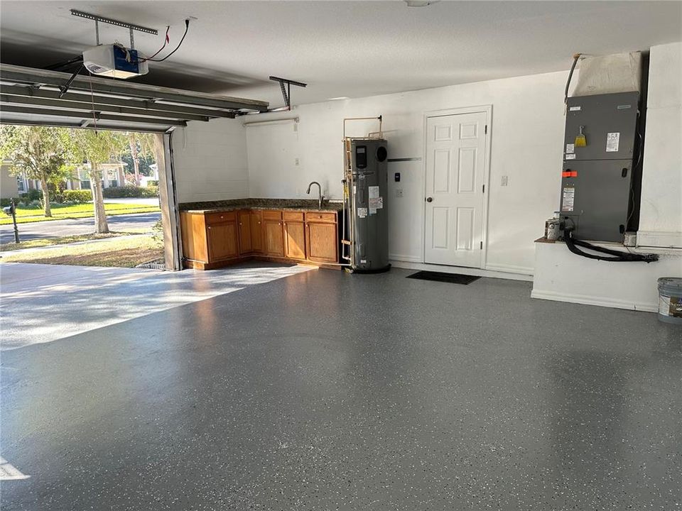 Freshly painted garage floor with cabinets, granite countertops, and sink