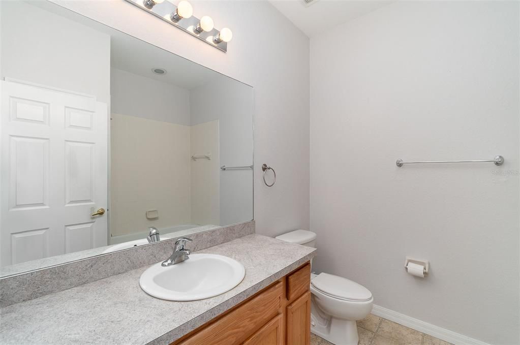 The guest bathroom features a wide vanity and a combined tub/shower.