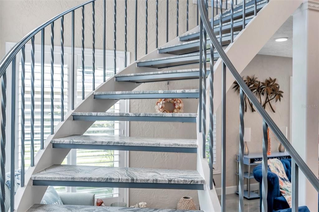 The beautiful sweeping curved staircase has textured quartz treads to match the custom fireplace in the living room.