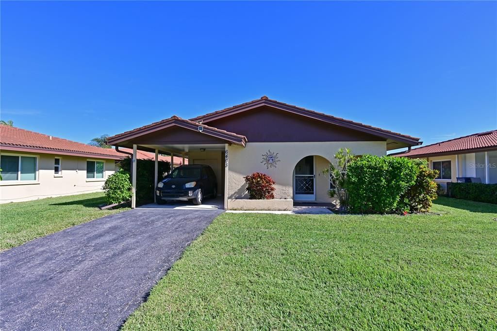 Spanish Style villa with tile roof, attached covered carport.