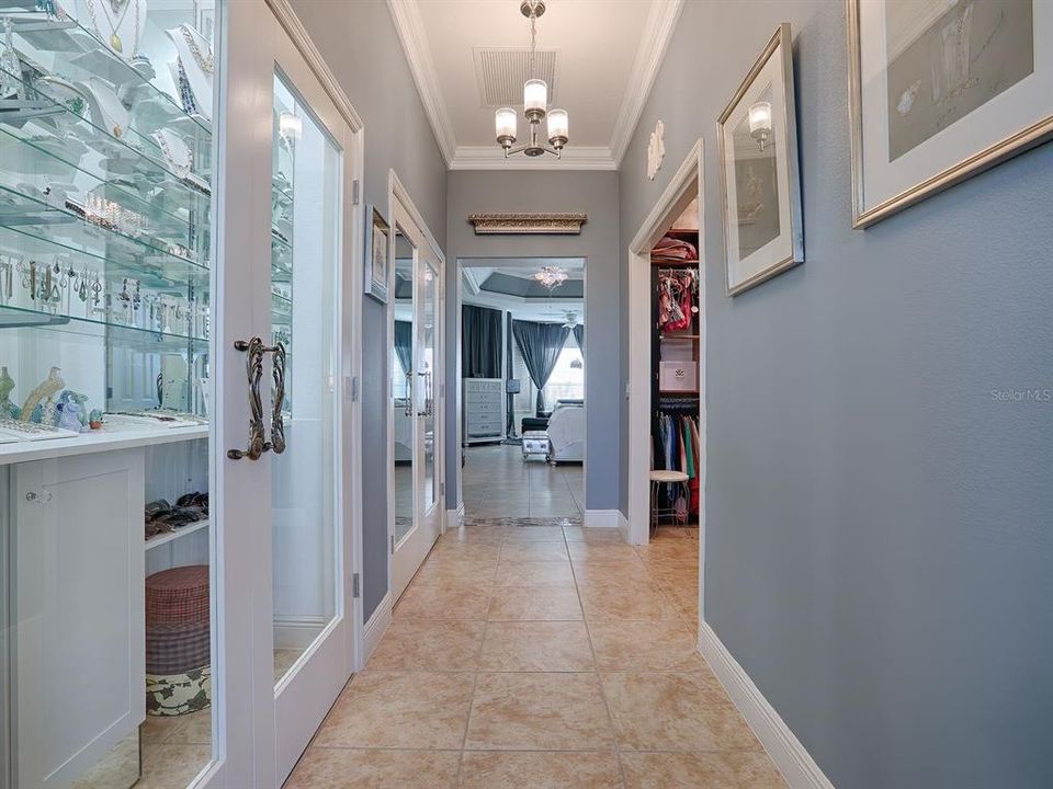 primary hall with custom closets and double glass doors