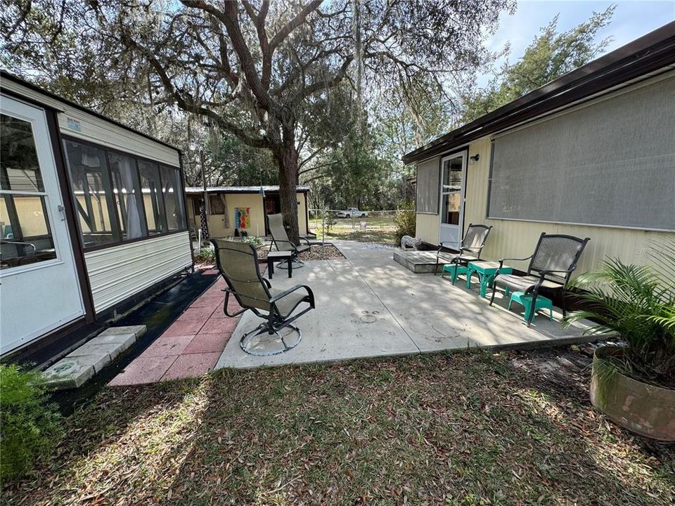 Open patio with screened room to the left & entry door to the FL room on the right. Workshop entrance pictured to the rear.