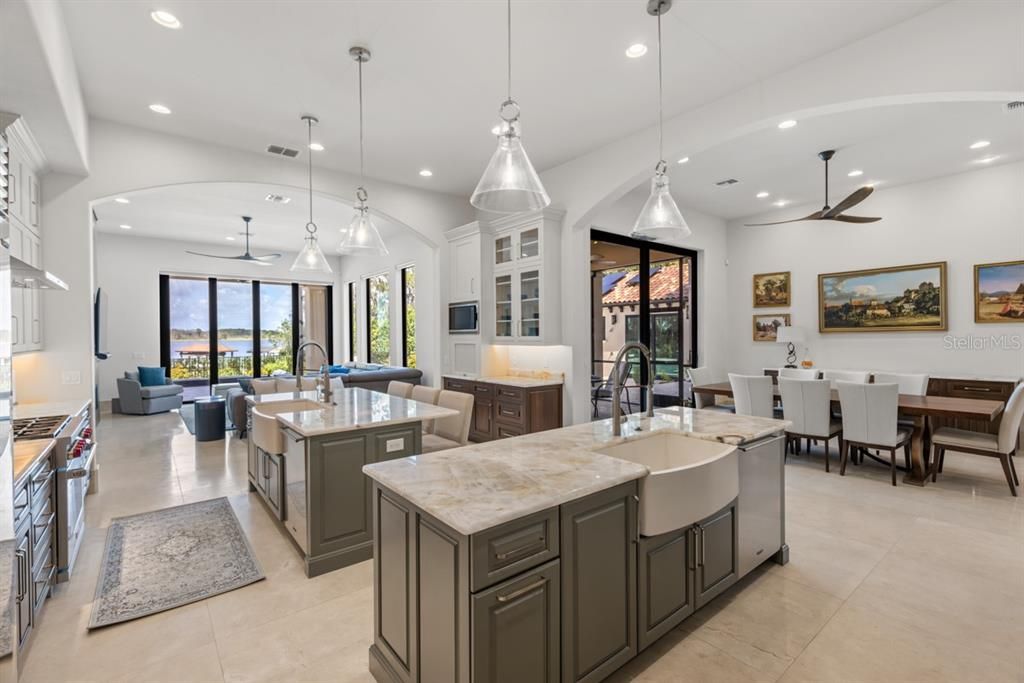 Highlighting a chef's dream kitchen, featuring Wolf ranges, a grand Sub-Zero fridge, and dual sinks and appliances, enveloped by abundant cabinetry and a warm ambiance for gatherings.