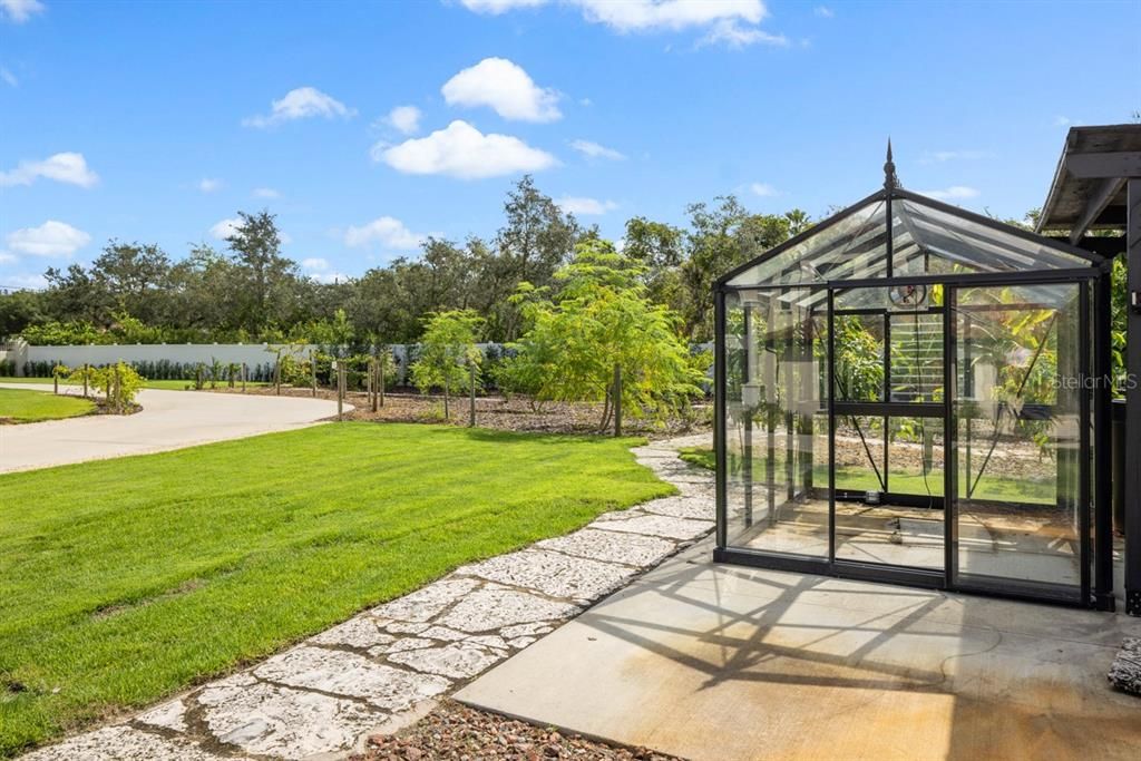 A glass greenhouse completes this haven for garden enthusiasts.