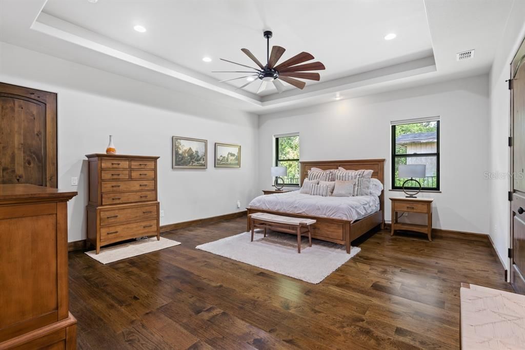 Refined master suite featuring rich hardwood floors and abundant natural light, an inviting and relaxing space.