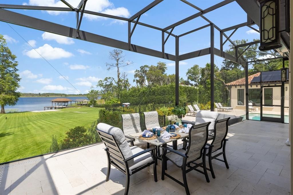 Screened-in dining area offering panoramic lake views flows from the adjacent outdoor kitchen space.