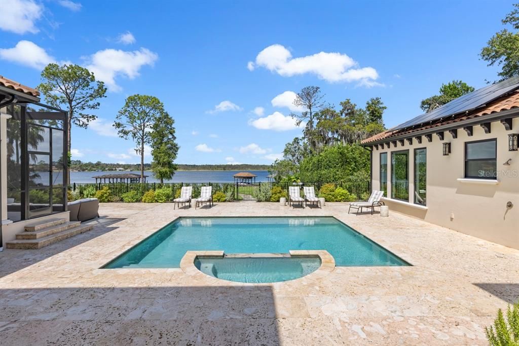 Luxurious pool with integrated hot tub, framed by stunning lake views offering an oasis of relaxation.